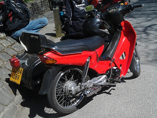 A bright red honda anf 125 innova with a sidecar attached